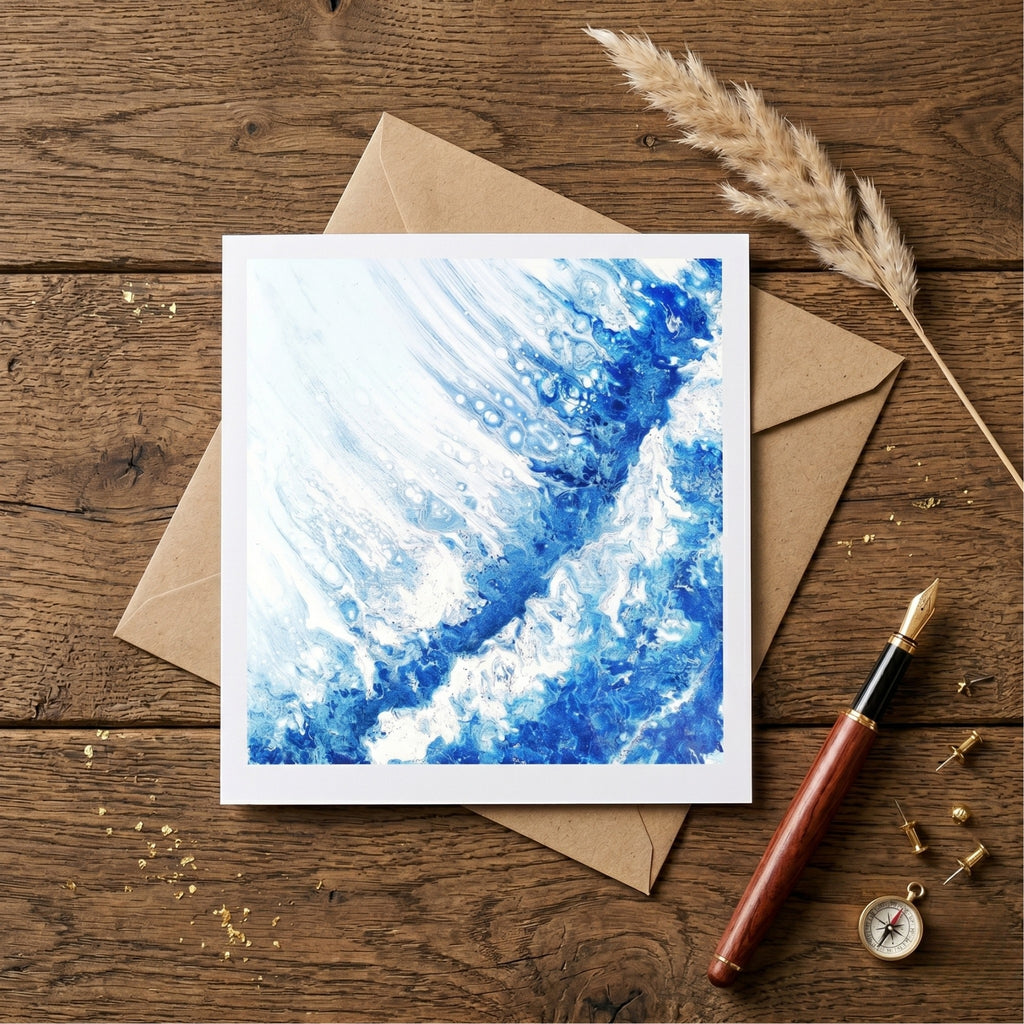 Greeting card with blue abstract design on a wooden surface with envelope and pen.