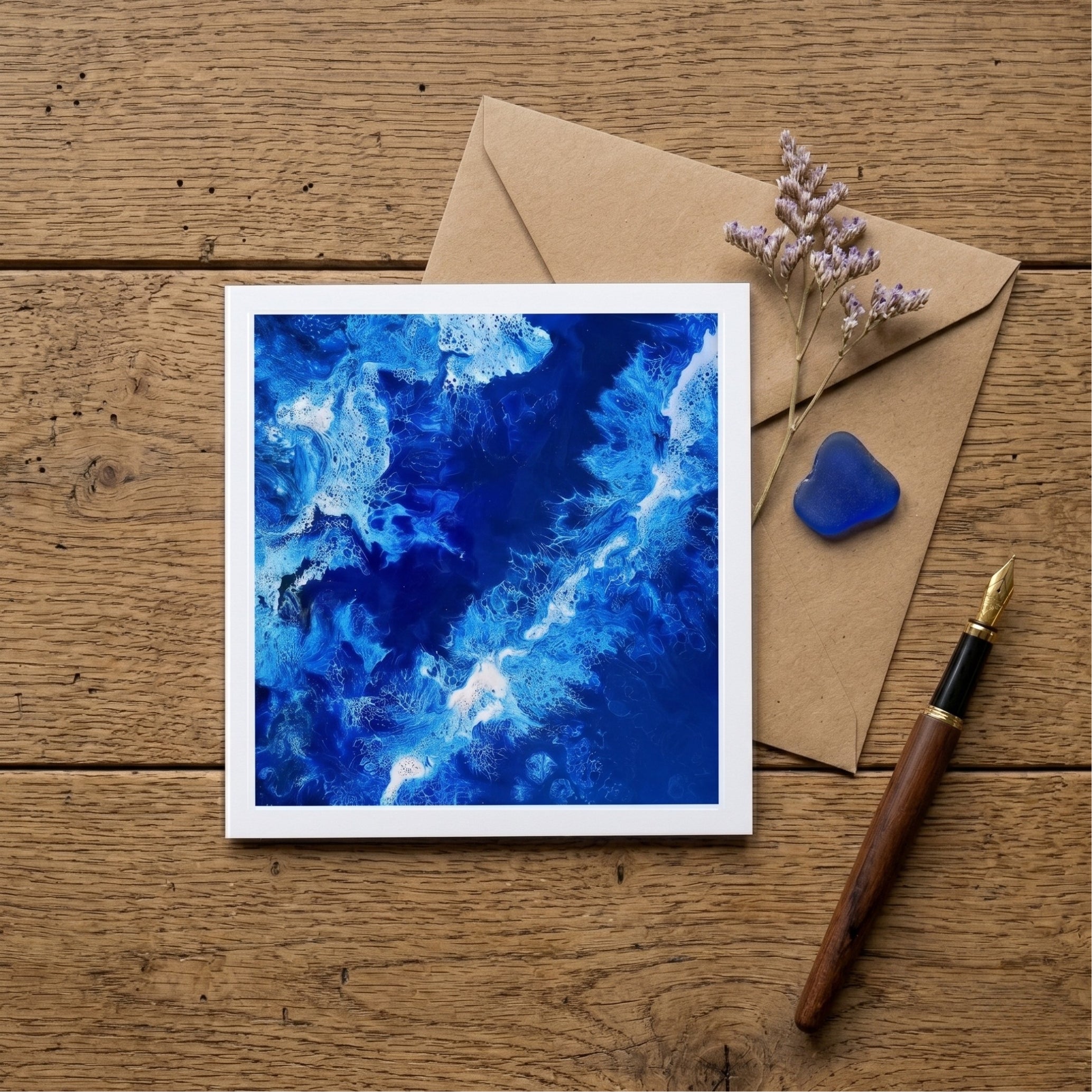 Blue abstract painting on a wooden surface with an envelope and pen.
