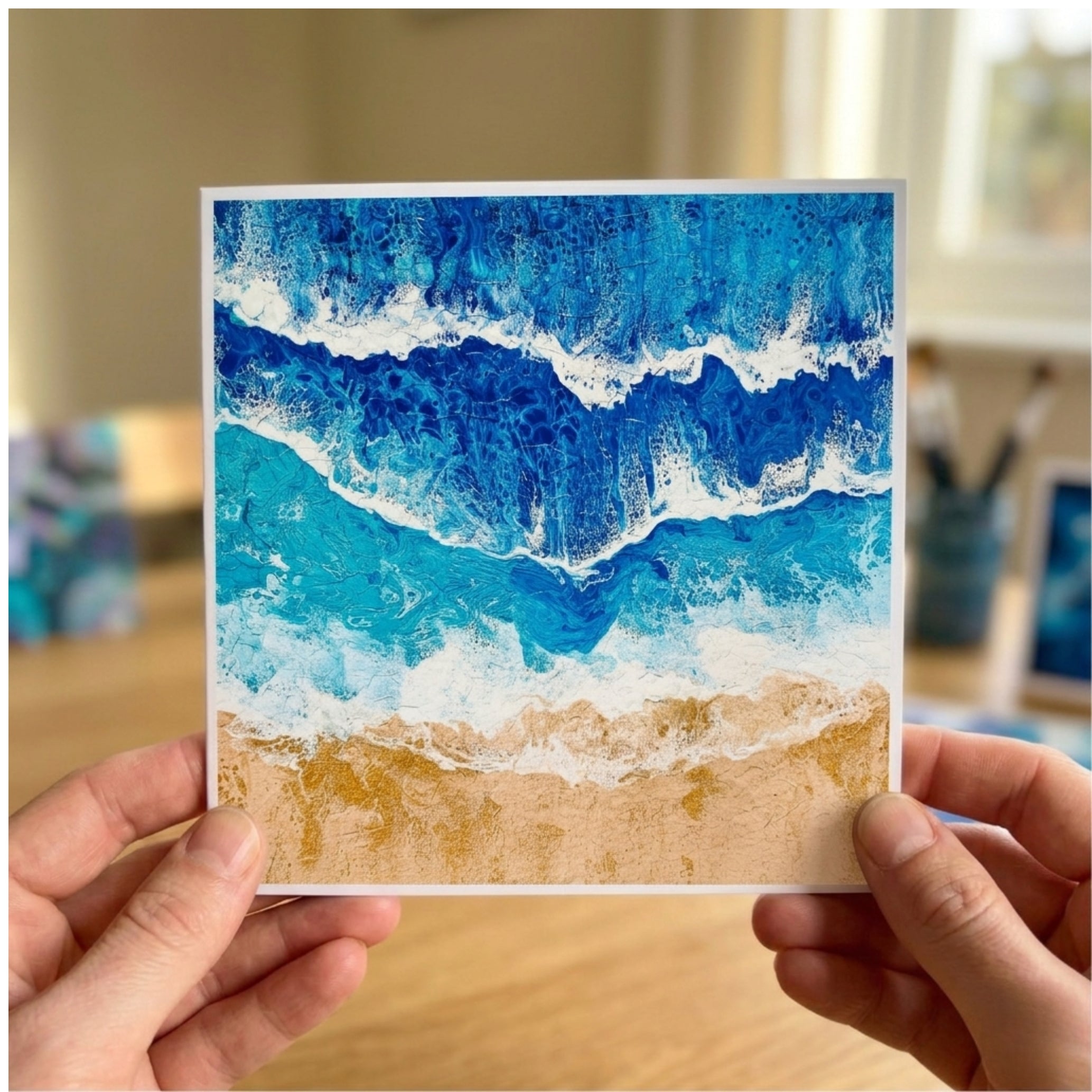 Card with a blue ocean wave design held by two hands.