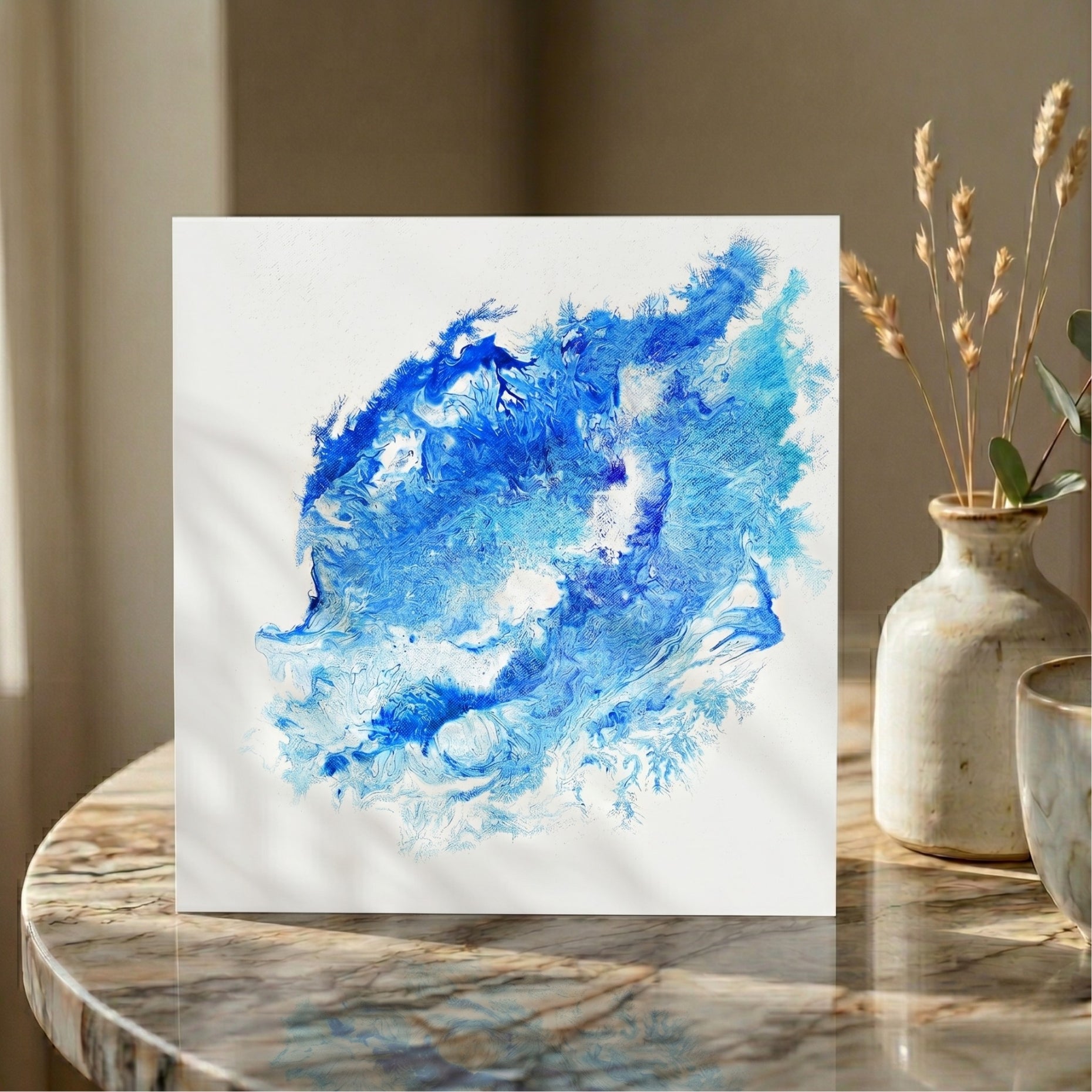  Abstract blue painting on a white card displayed on a marble surface with decorative vases.