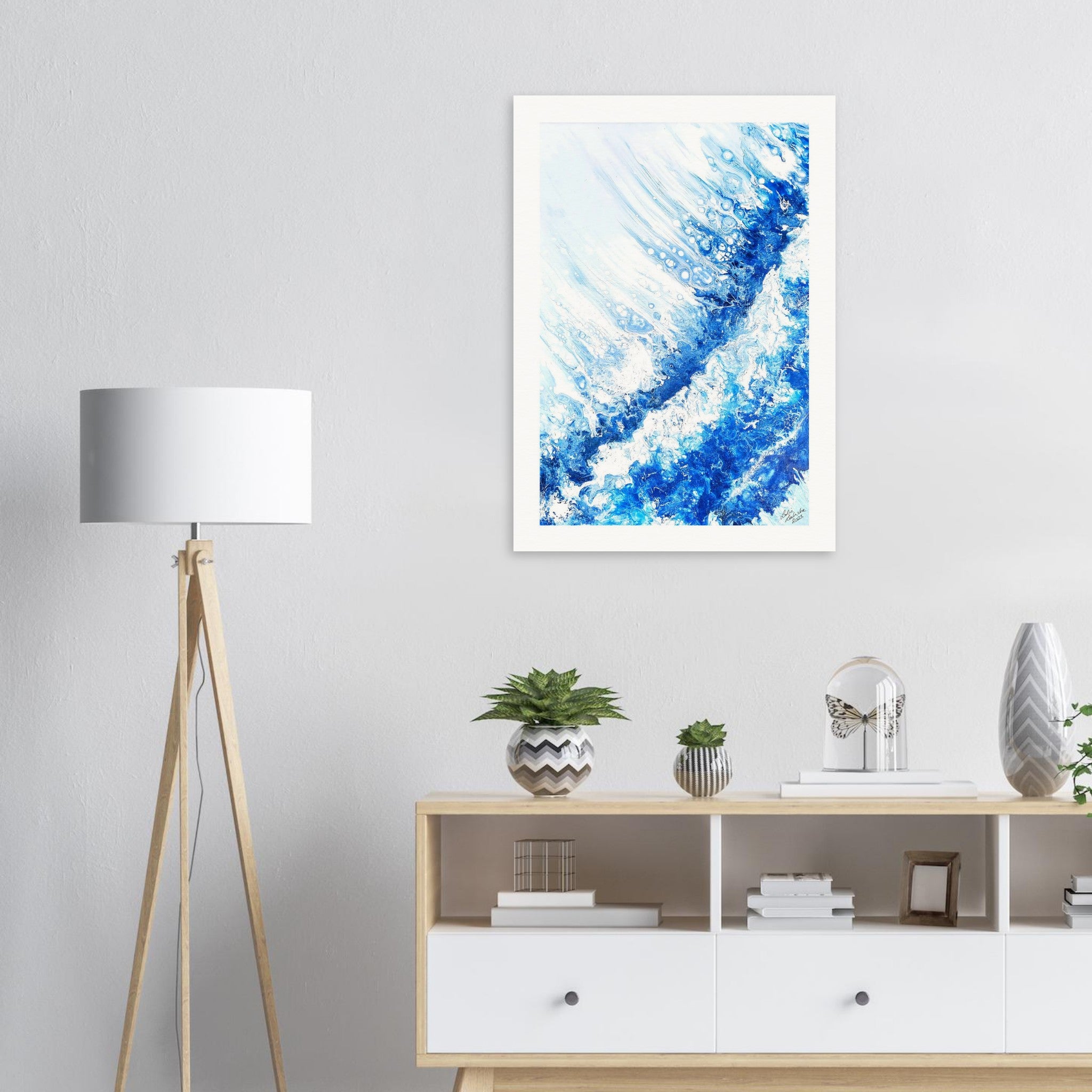 Framed abstract blue artwork on a wall above a wooden sideboard with decor items.