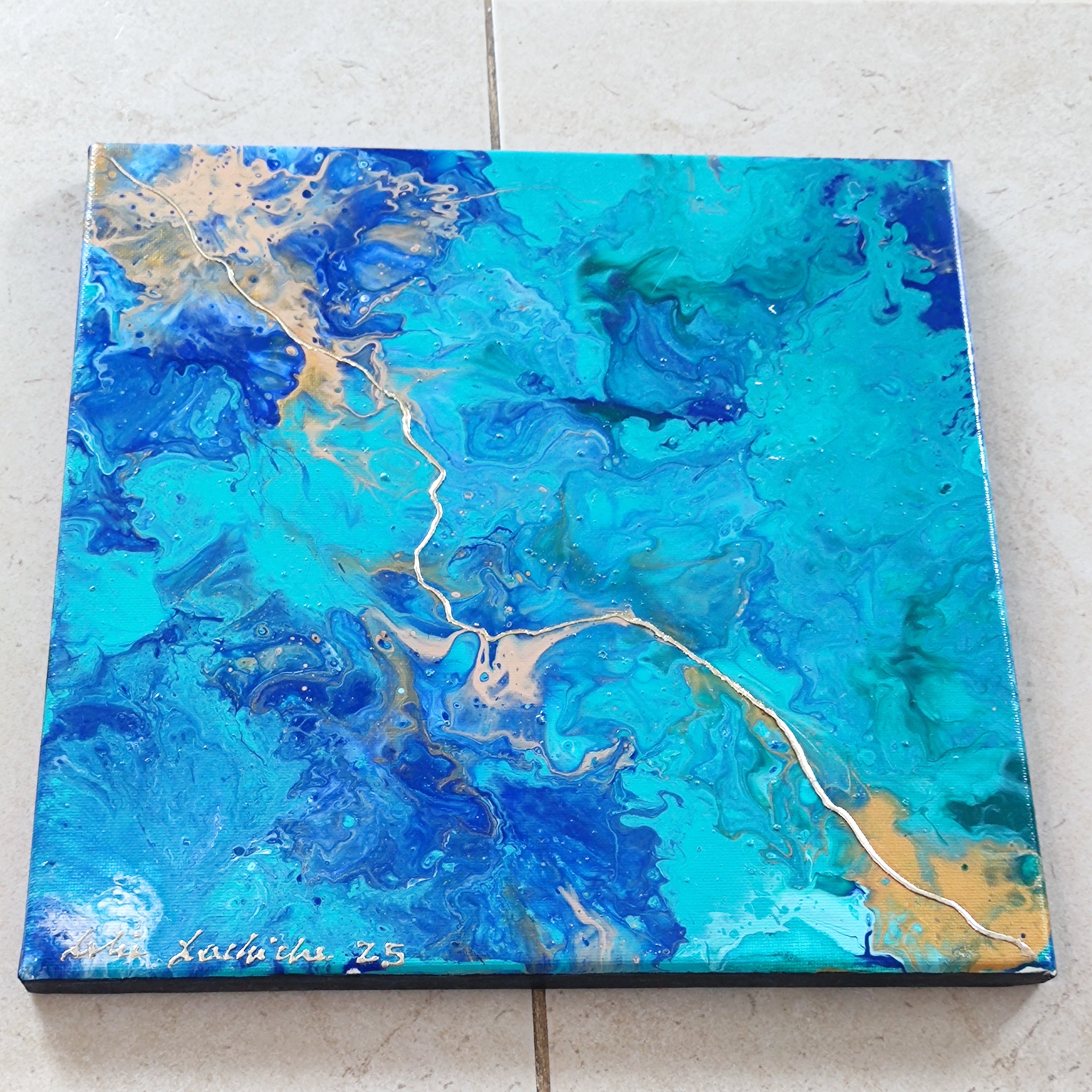 Abstract art piece with blue and gold colors on a tiled floor