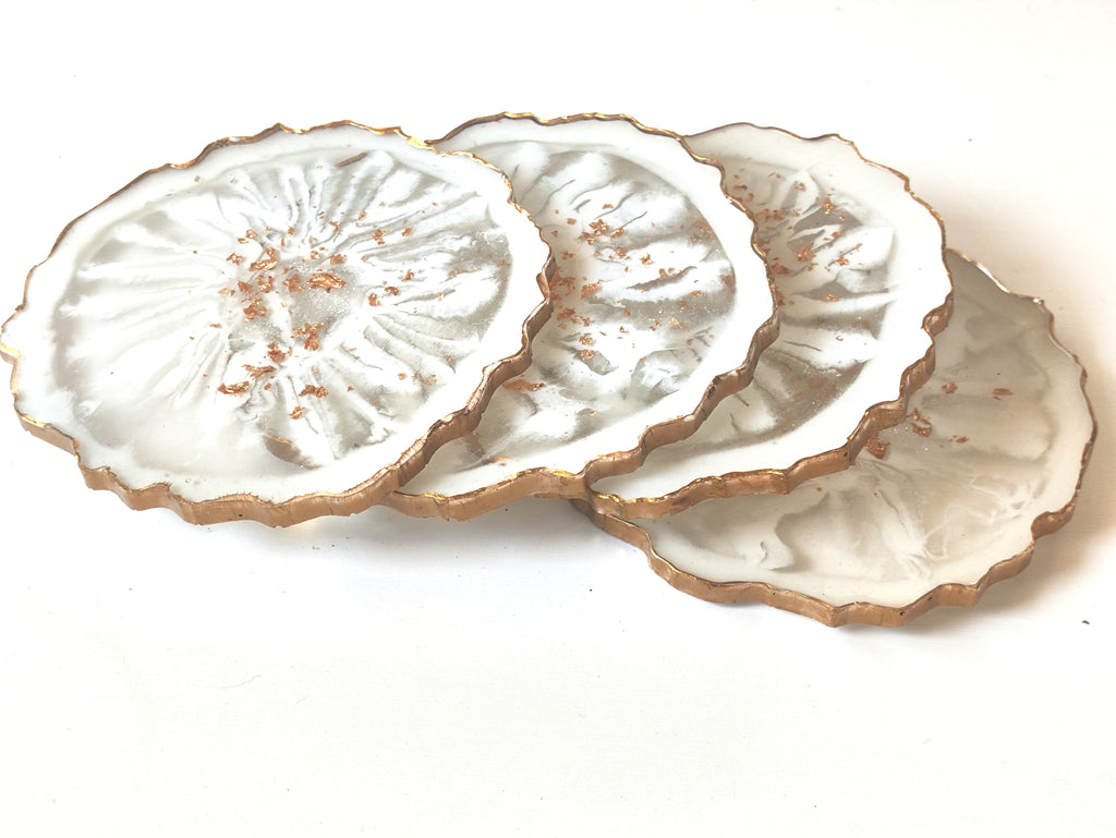 Set of three white ceramic coasters with gold edges on a white background
