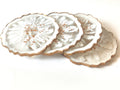 Set of three white ceramic coasters with gold edges on a white background