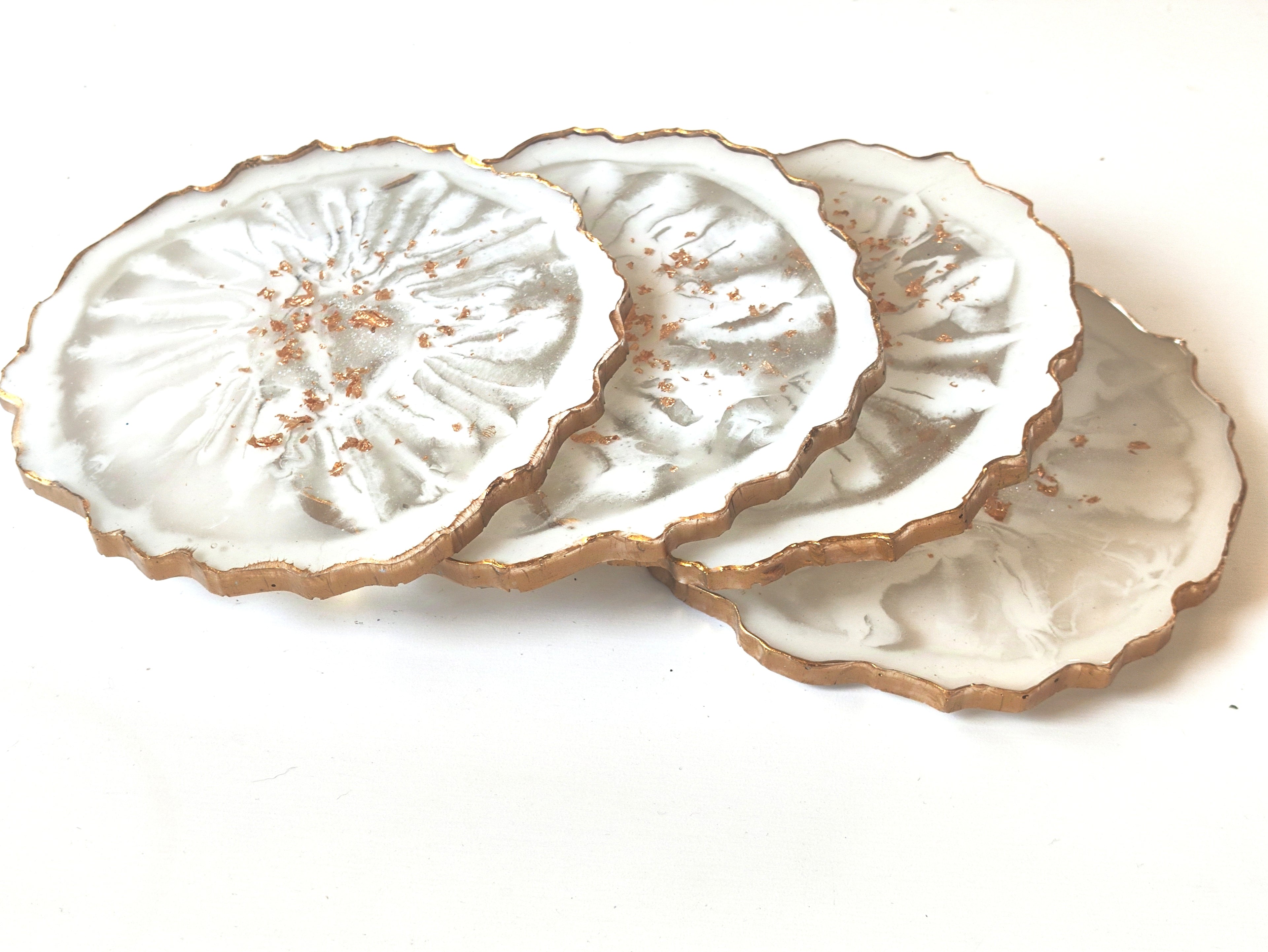 Set of three white ceramic coasters with gold edges on a white background