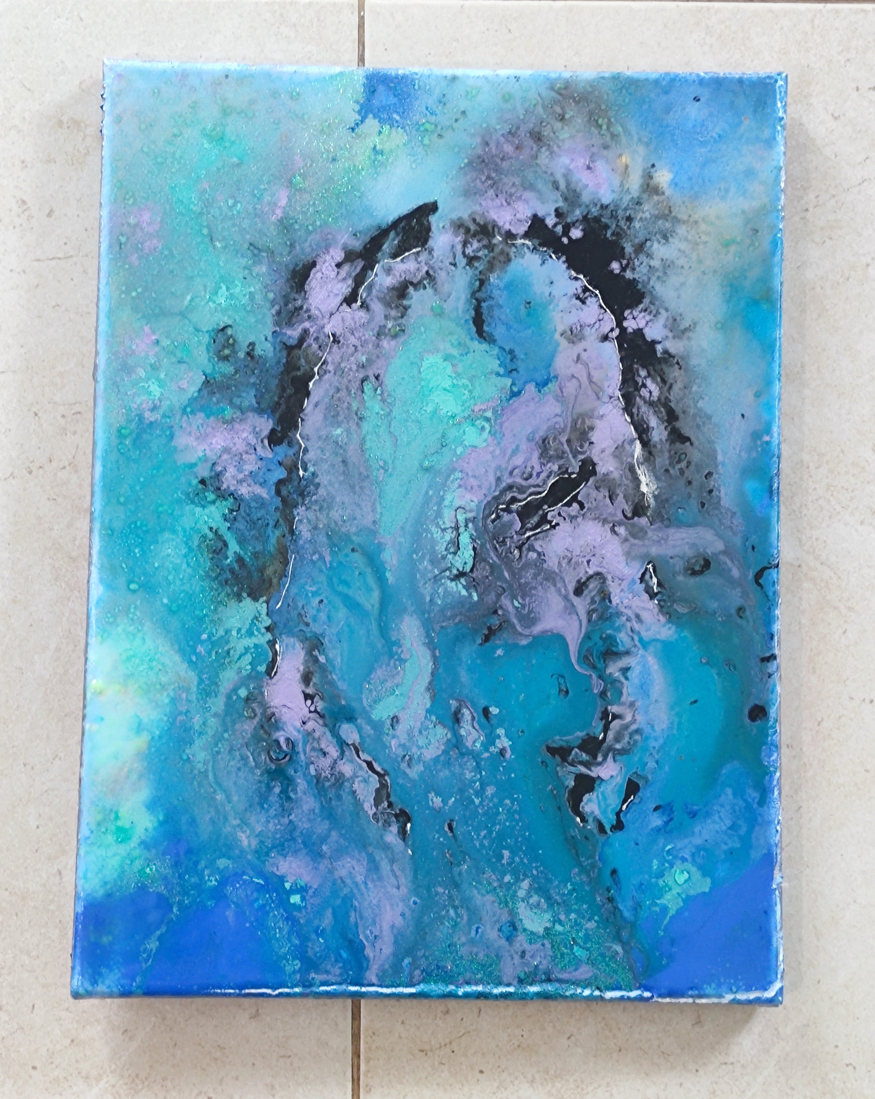 Abstract painting with blue and black colors on a textured wall.
