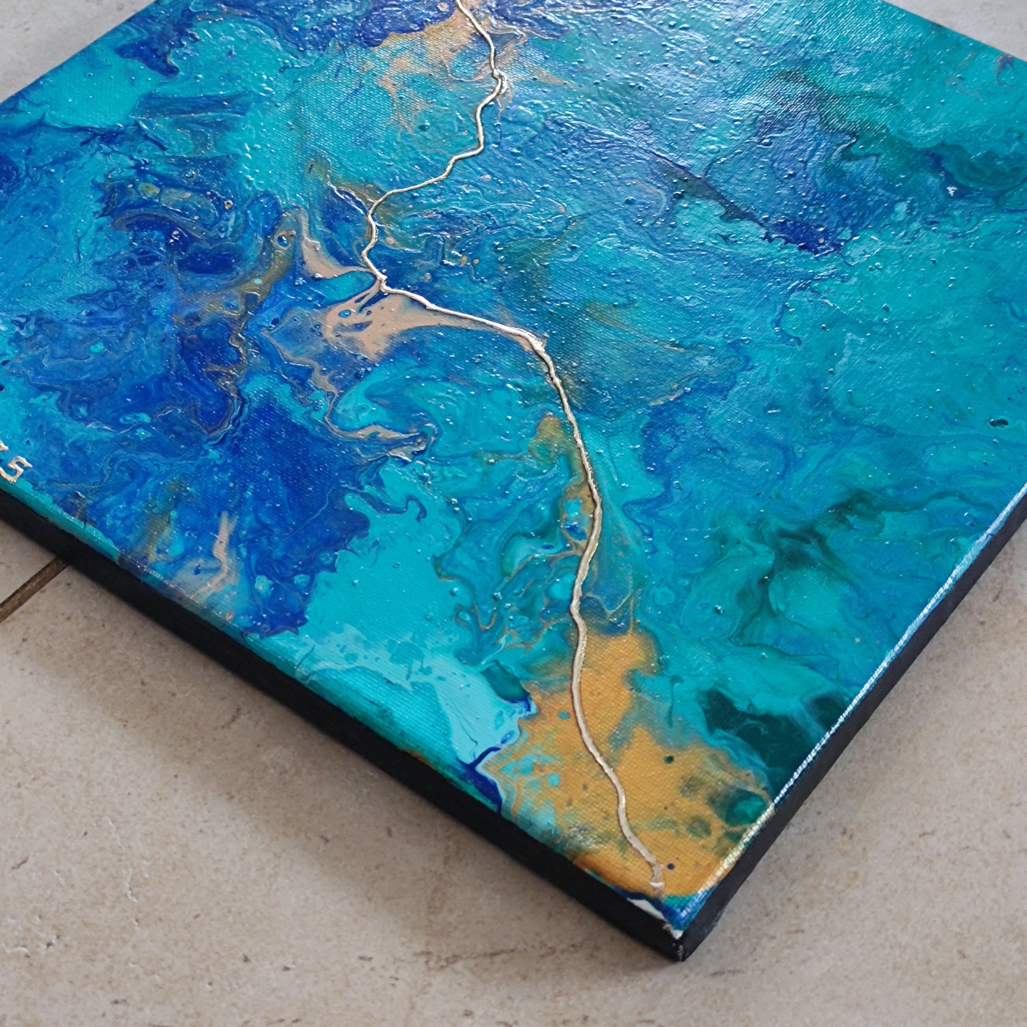 Abstract art piece with blue and gold colors on a tiled floor