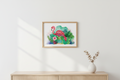 Framed artwork of a flamingo and flowers on a wall above a wooden cabinet.