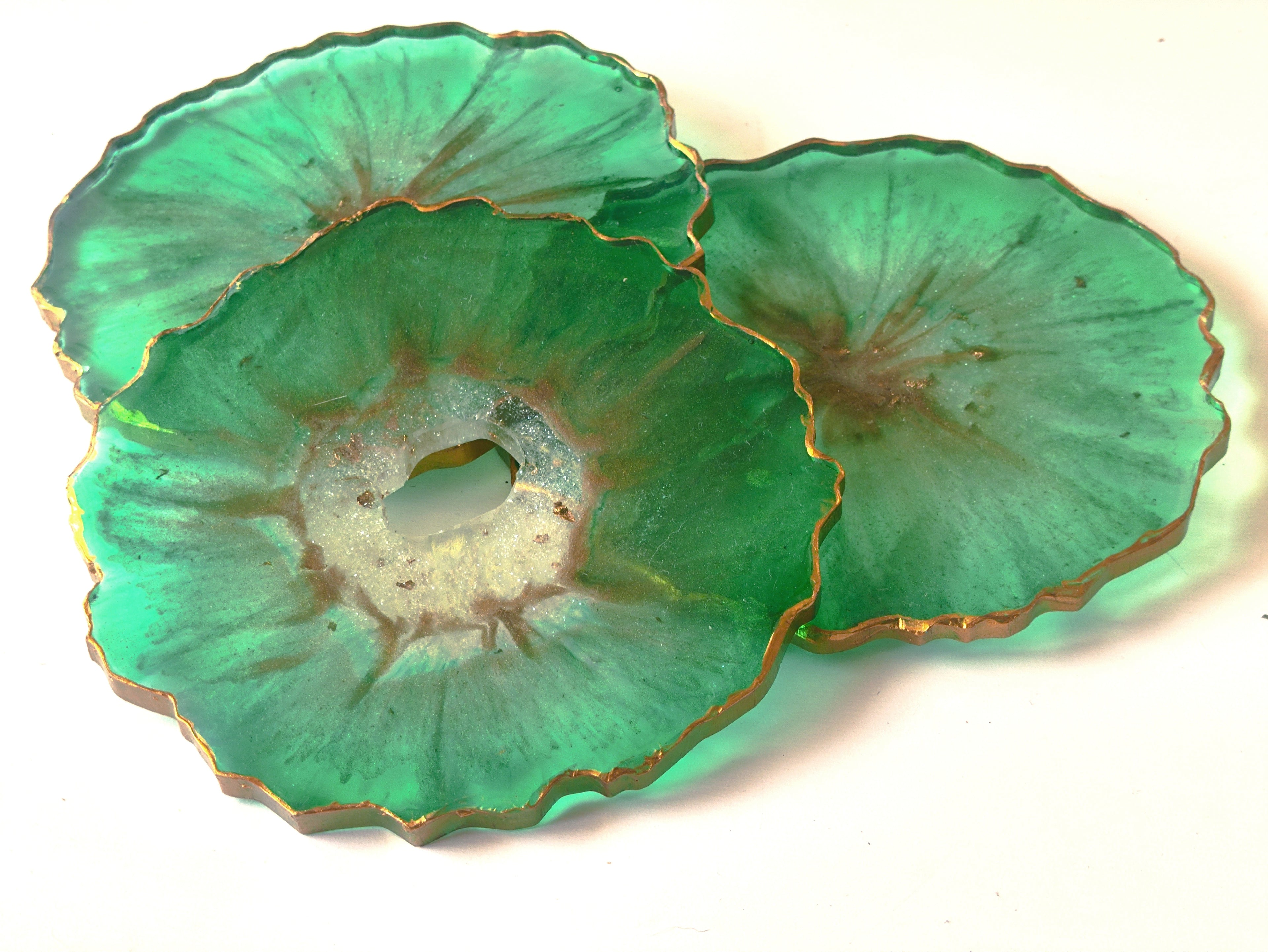 Two green agate slices with gold edges on a white background
