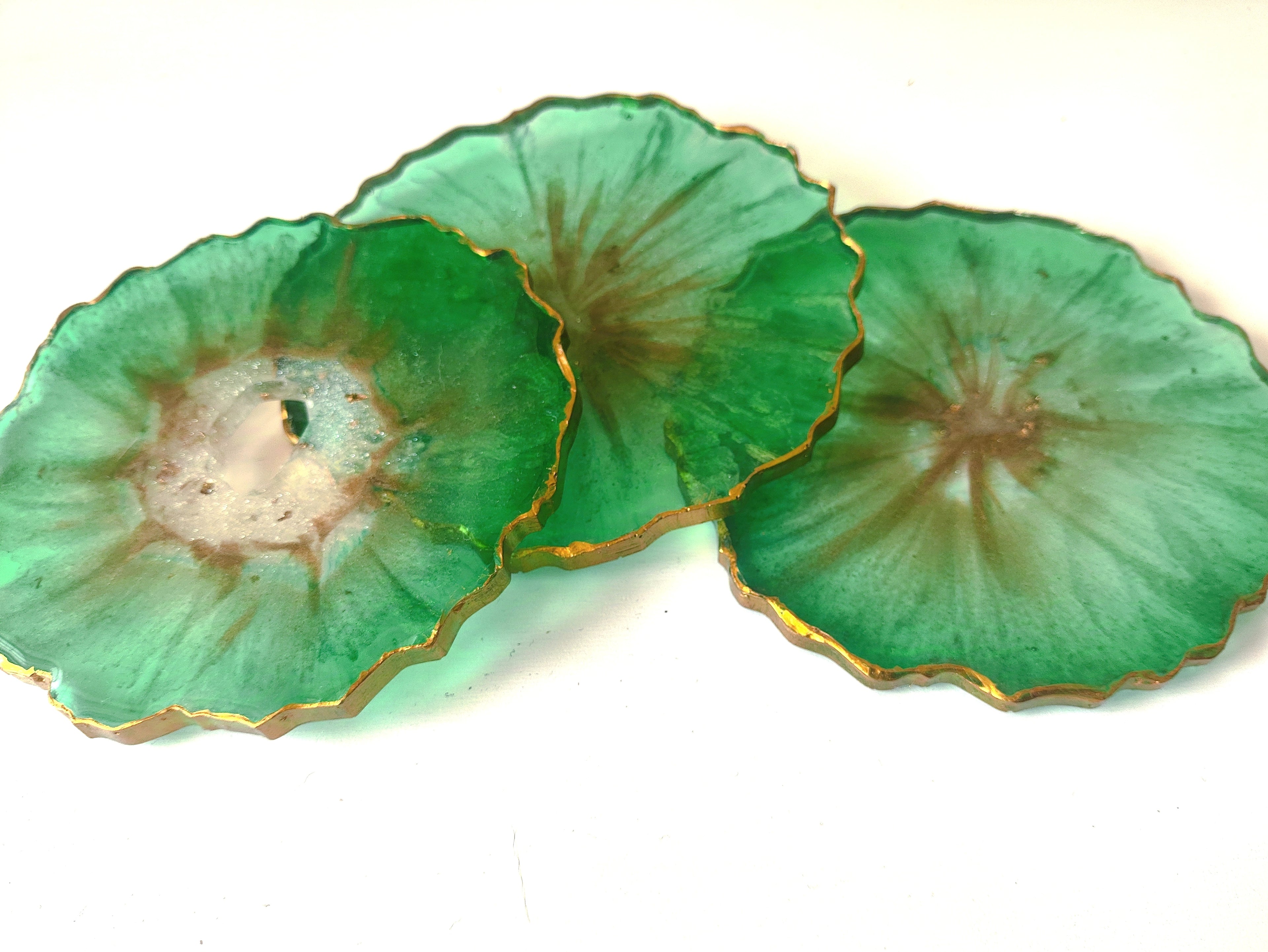 Three green ceramic plates with gold rims on a white background