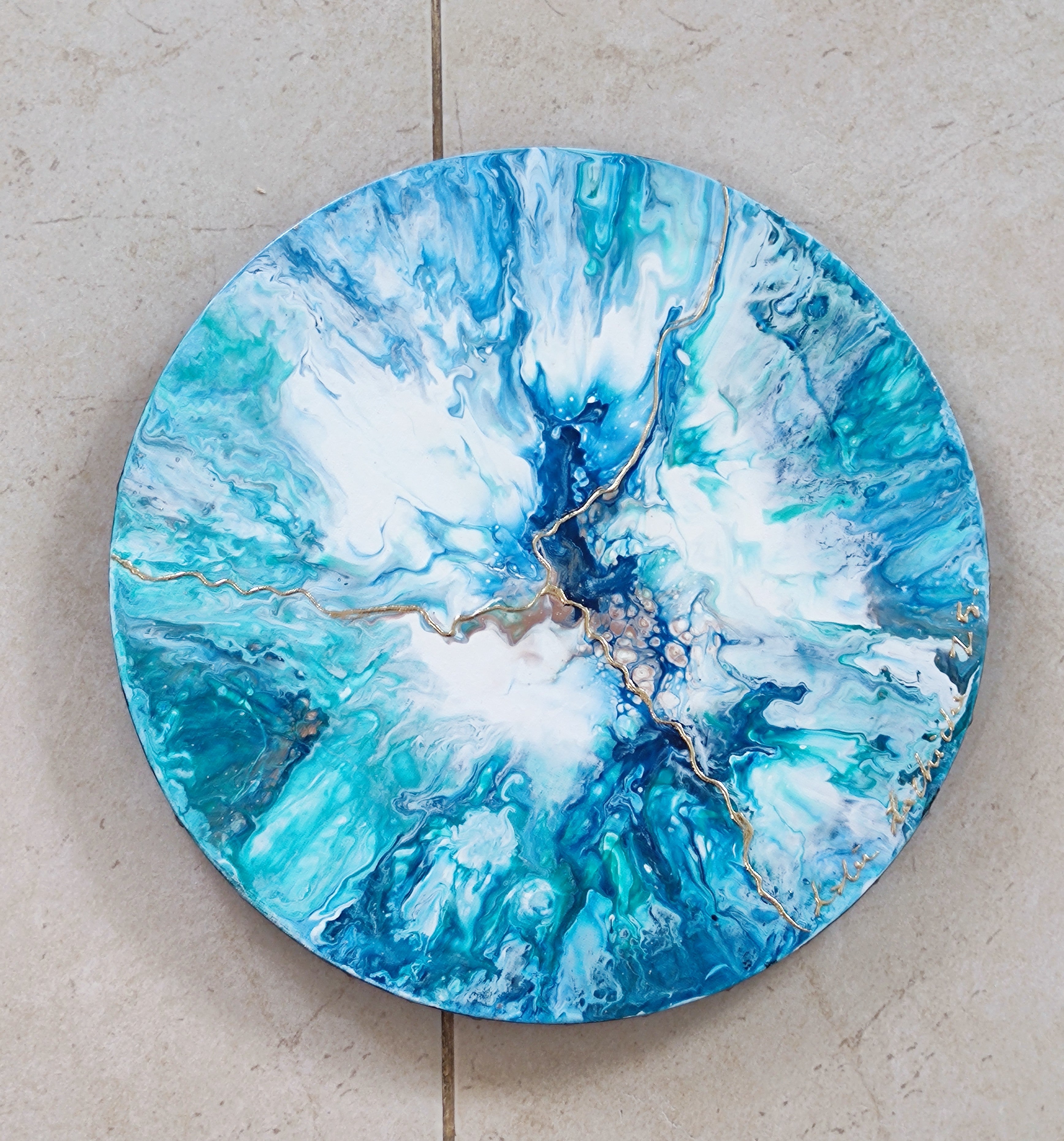 Round blue and white abstract art piece on a beige surface