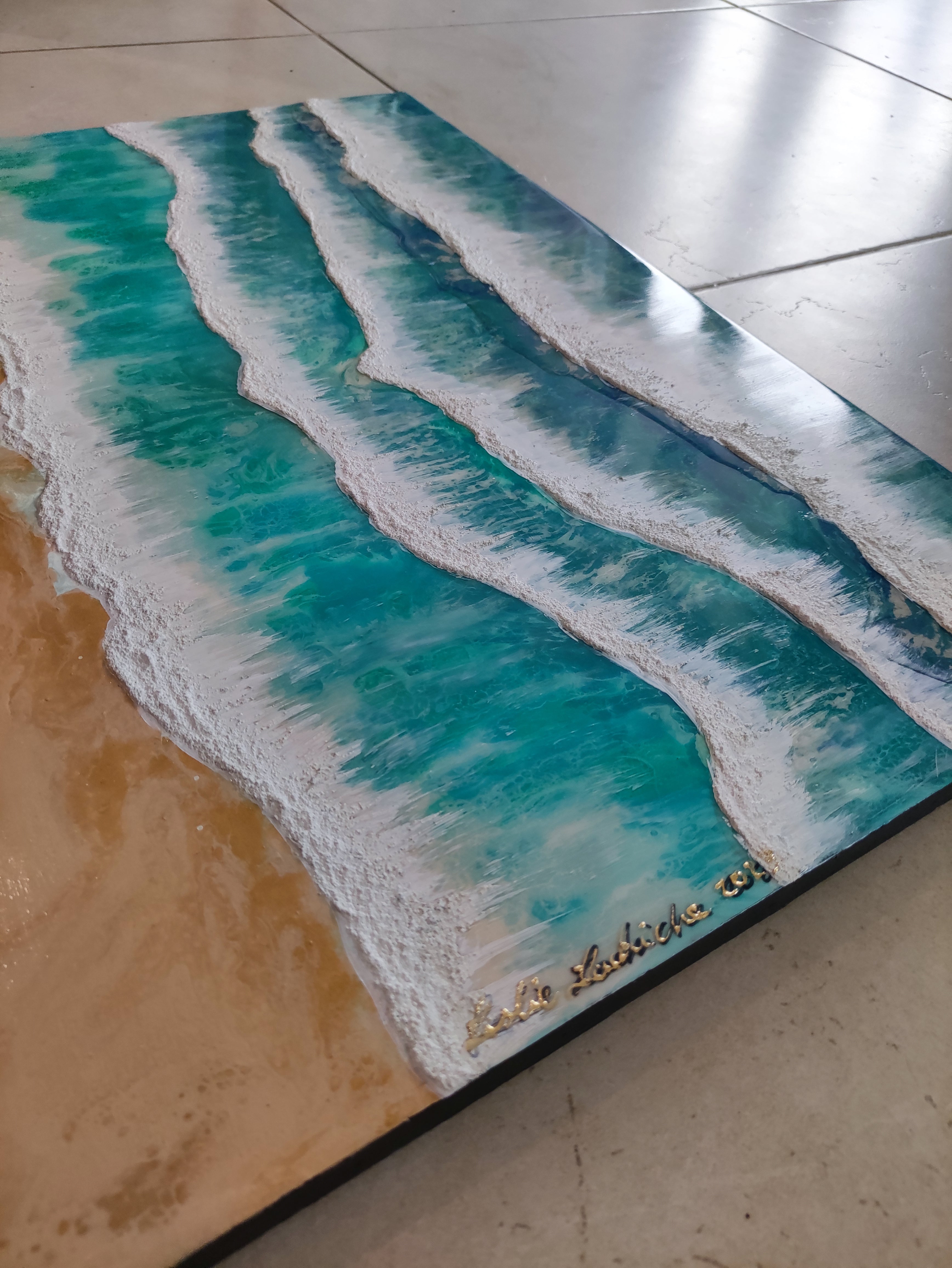 Artistic depiction of ocean waves and sand on a flat surface
