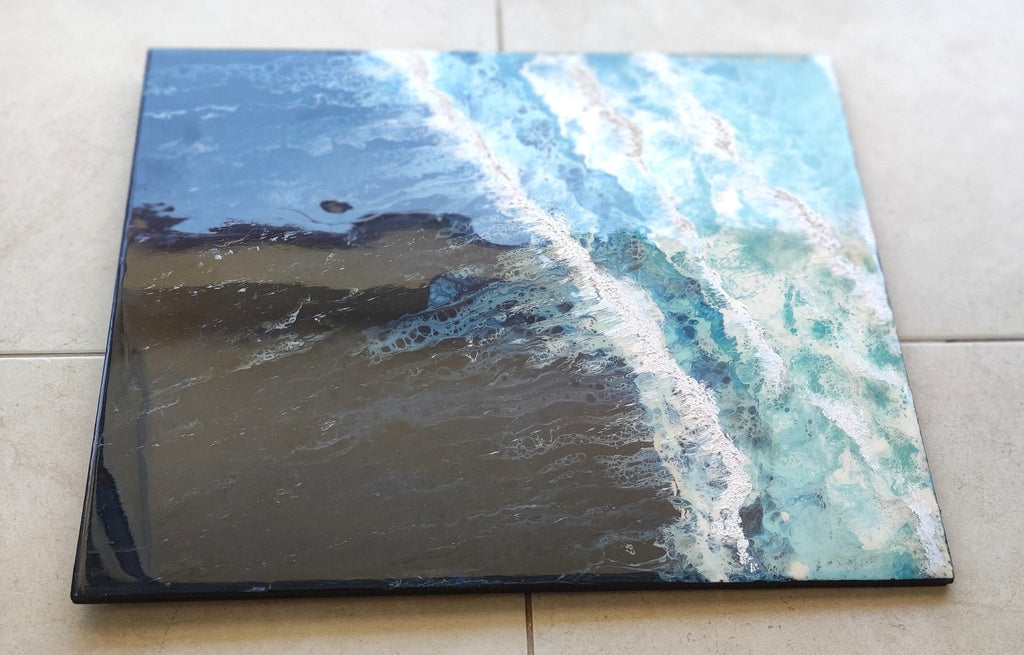 Square canvas print of a beach scene with blue sky and ocean waves on a tiled floor.