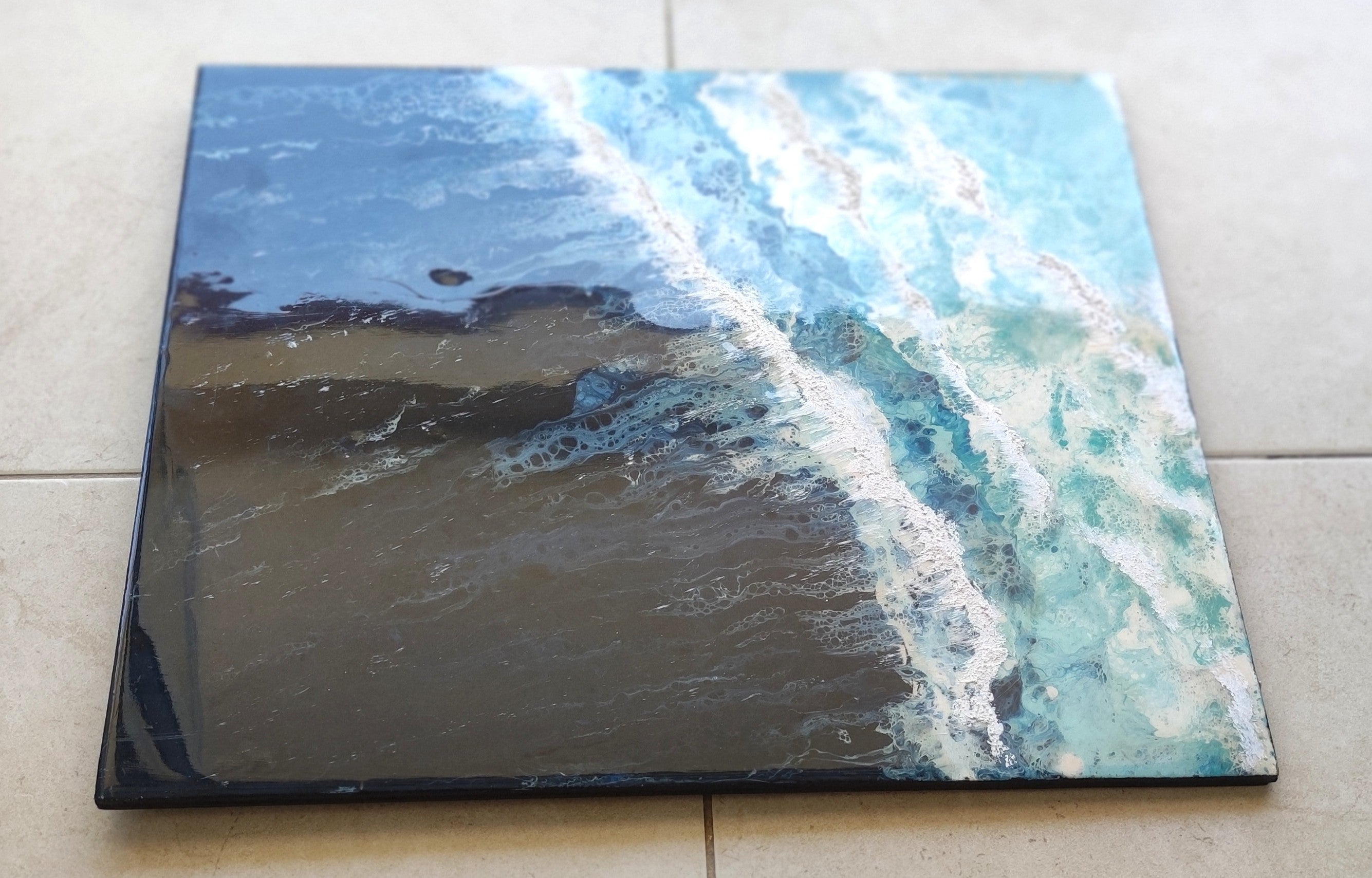 Square canvas print of a beach scene with blue sky and ocean waves on a tiled floor.