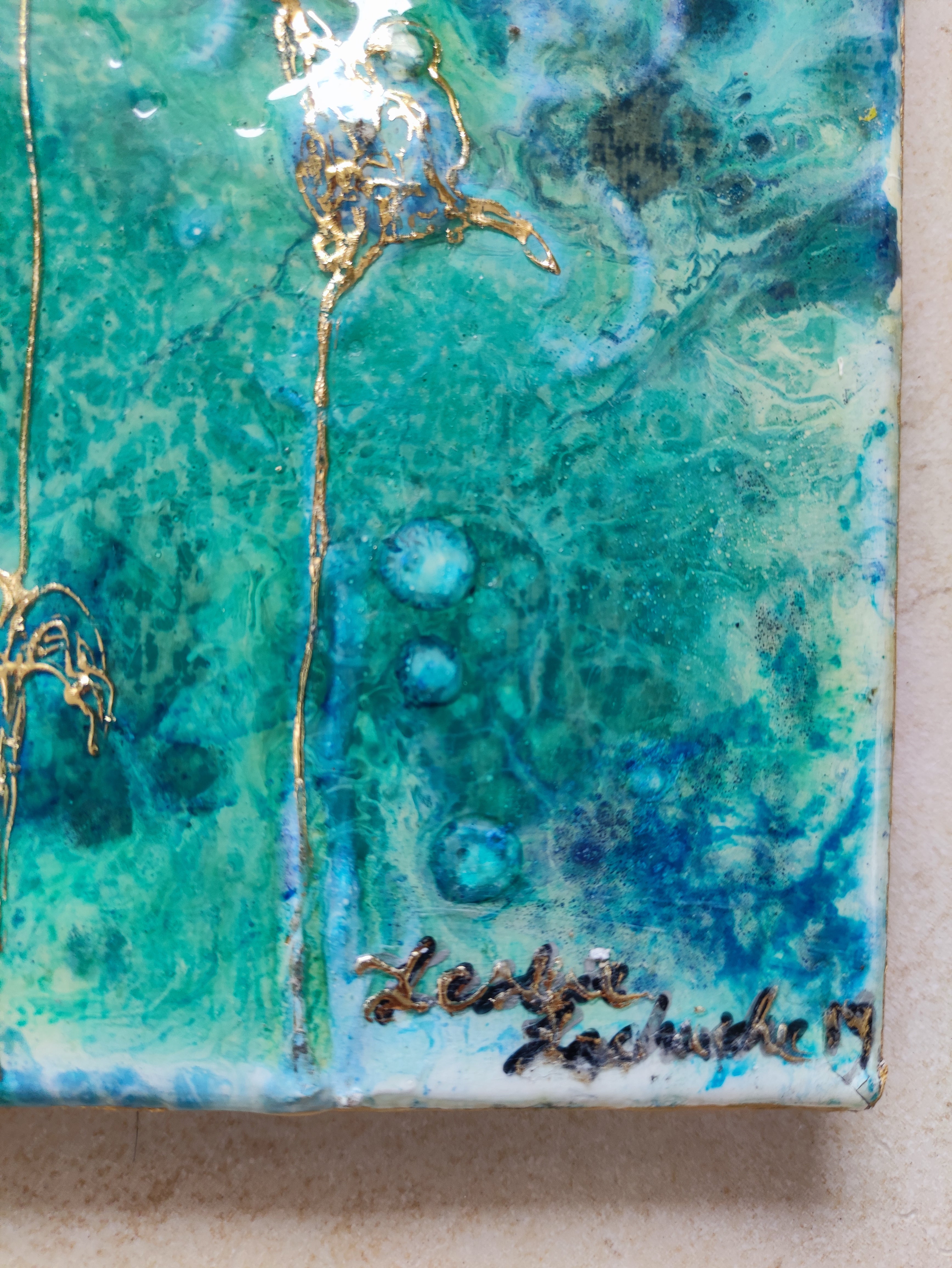 Close-up of a textured green and blue surface with gold accents and a signature.