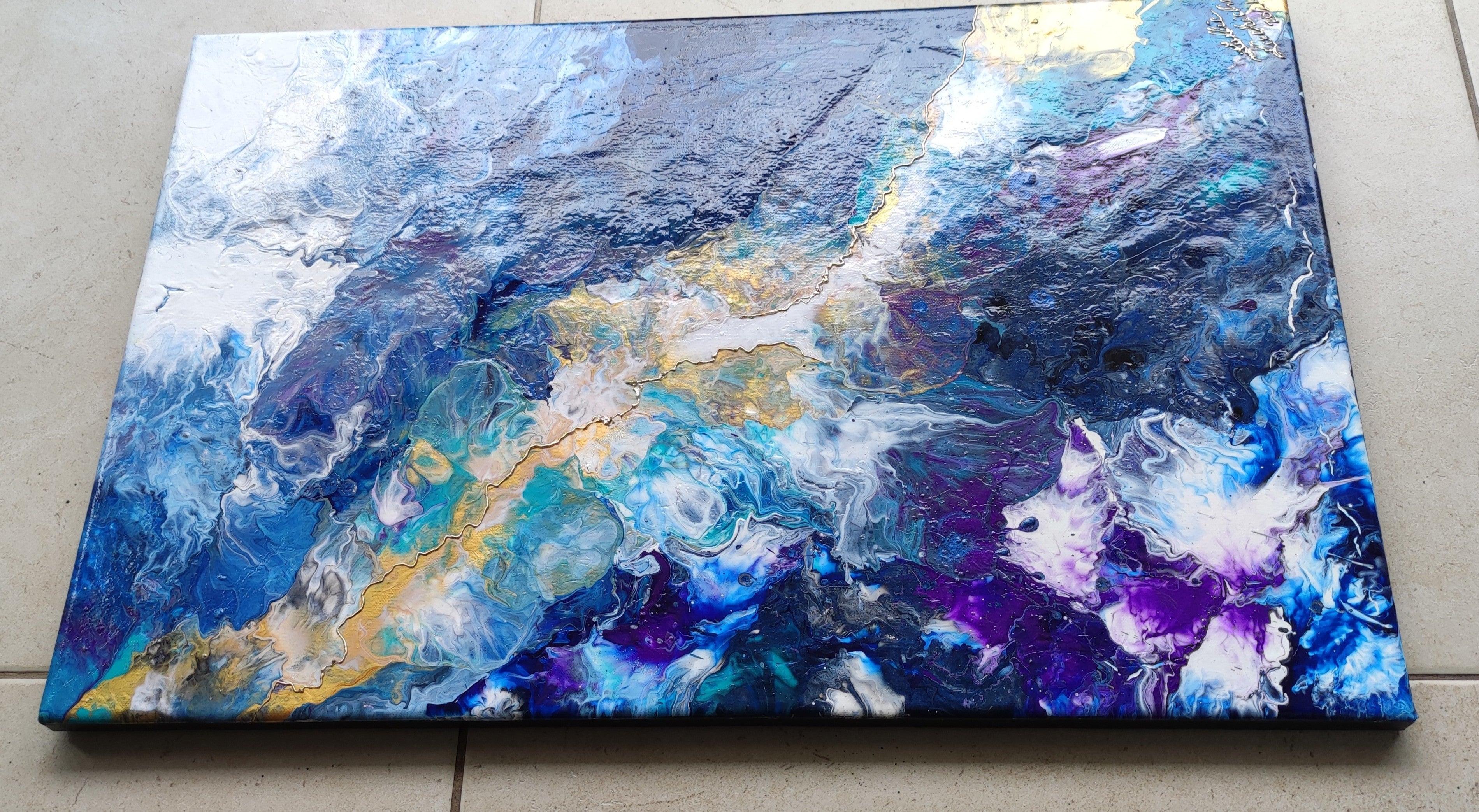 Abstract painting with blue, purple, and gold colors on a flat surface