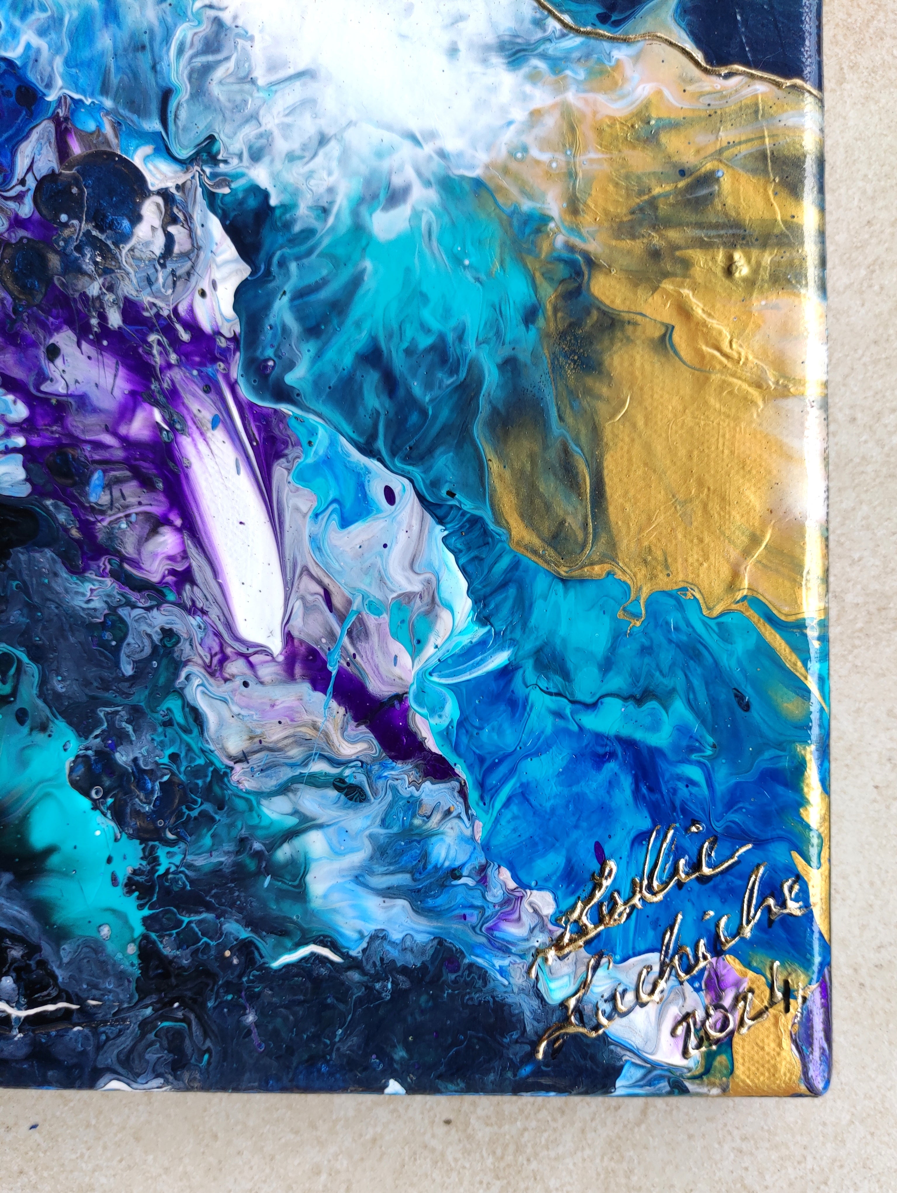 Abstract art piece with blue, purple, and gold colors on a textured surface.