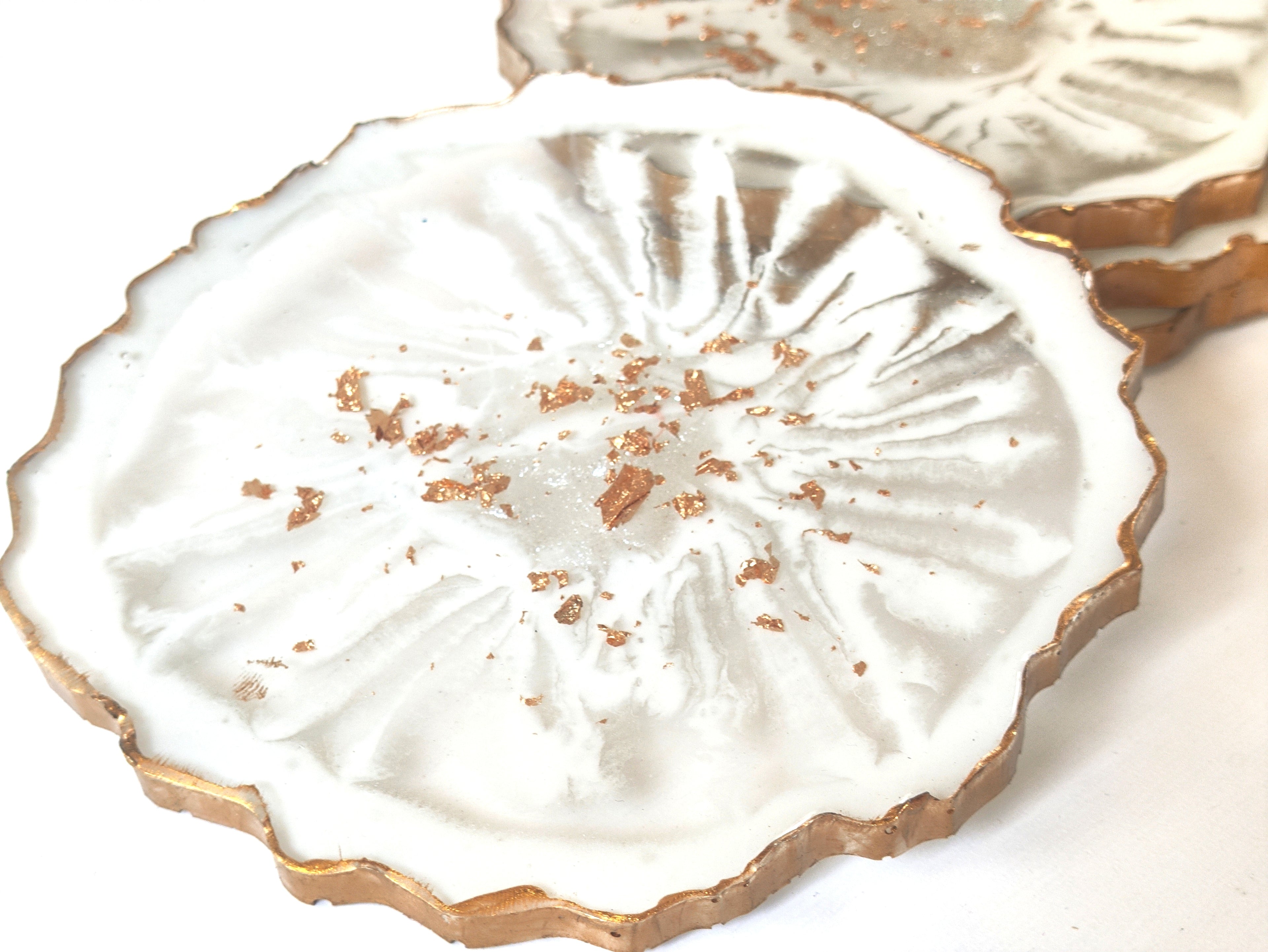 Decorative white coaster with gold accents on a white background